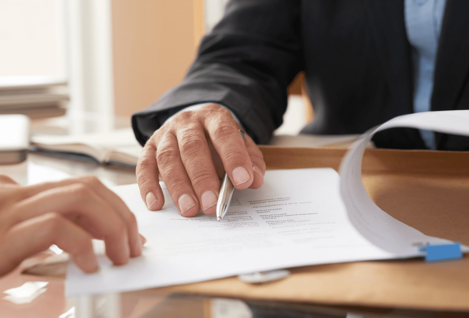 Mano de un hombre con aspecto ejecutivo con un bolígrafo en la mano señalando un documento