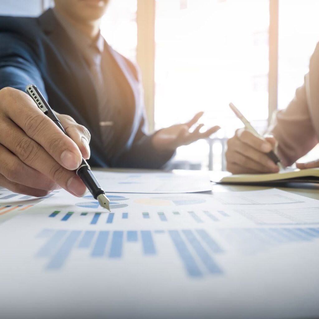 Persona escribiendo sobre unos papeles con unos gráficos